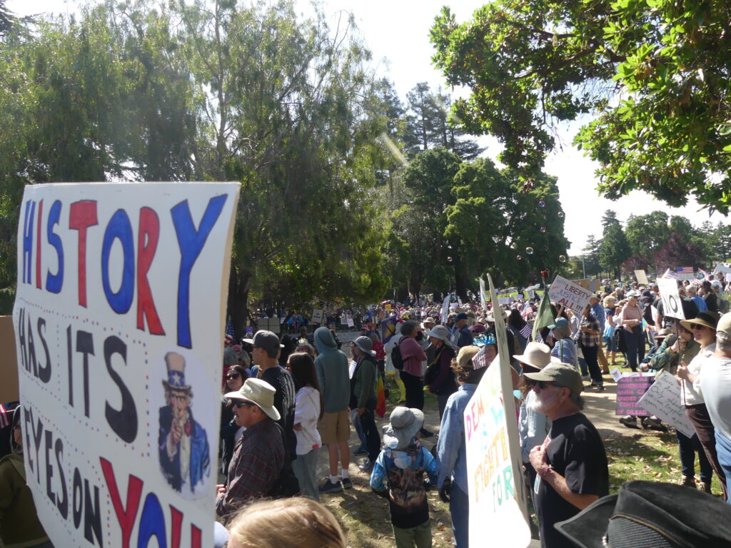 View over crowds with sign in front that says "history has its eyes on you"